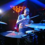 Josh Bannister playing drums with lazer lights in the background