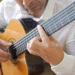 Classical guitarist wearing white shirt, playing guitar